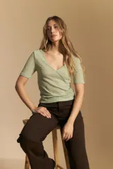 Top de manga corta confeccionado en tejido jacquard con textura en relieve. Presenta escote en V y un diseño frontal con líneas diagonales que crean un efecto cruzado.