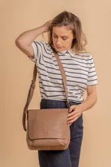 Bandolera de diseño simple con tapa frontal, confeccionada en material símil cuero. Cuenta con correa ajustable, división interna y bolsillos internos para mayor organización.