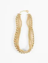 Collar dorado de tres hilos con cuentas redondas de diferentes tamaños.