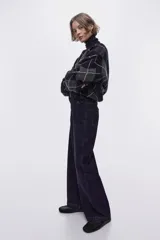 Jean wide leg de tiro alto en denim de algodón azul, con costuras frontales verticales y bolsillos simulados con solapa y botones en la parte delantera.