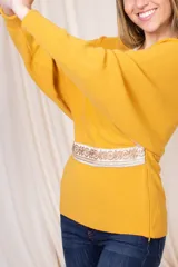 Sweater de lanilla color mostaza, con escote en V, corte entallado y guarda bordada en la cintura.