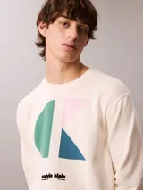 Sweater Calvin Klein de corte relajado y color blanco, con cuello redondo, mangas largas y puños de canalé. Presenta un diseño gráfico de monograma CK en color block con bloques en verde, rosado y azul, acompañado del logotipo de la marca estampado en el pecho.
