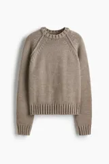 Buzo de punto suave con cuello redondo, manga raglán y costuras decorativas visibles. Presenta terminaciones acanaladas en cuello, puños y ruedo.