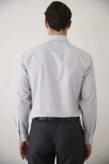 Camisa de vestir blanca de manga larga, con cuello clásico y cierre frontal de botones. Presenta un corte entallado que se adapta a la silueta.