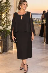 Vestido midi negro confeccionado en gasa, con sobrecapa fluida, mangas abiertas y cuello redondo con bordado de pedrería y detalle de abertura en lágrima.