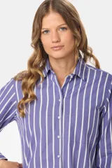 Camisa holgada de manga larga, color azul con rayas verticales blancas, cuello clásico y bolsillo en el pecho.