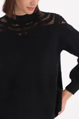 Sweater negro de punto con diseño de crochet en la parte superior del pecho y hombros, cuello redondo y mangas largas con puños ajustados.