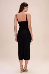Vestido midi negro de lycra de corte ajustado, con tirantes finos y detalles de aplicaciones florales blancas con centros negros en la zona del busto.