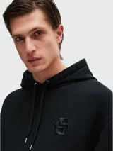 Sudadera negra con capucha y cordones ajustables, bolsillo tipo canguro y logo bordado en el pecho.