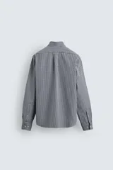Camisa de corte regular fit confeccionada en tejido de algodón con efecto lavado. Presenta cuello abotonado, manga larga con puños abotonados, bolsillo en el pecho y cierre frontal con botones.