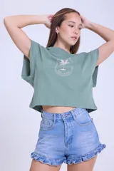 Remera verde de algodón con mangas cortas con efecto de hombrera y estampado con una palmera y la frase "Welcome to La Guia Summer Vacation".