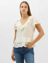 Blusa de satén color crema con acabado texturizado, escote en V con volados, mangas cortas acampanadas y diseño péplum con doble nivel de volados en la parte inferior.