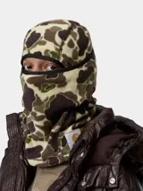 Máscara tipo pasamontañas Carhartt confeccionada en tejido polar con estampado de camuflaje. Presenta un diseño de cobertura total con abertura para los ojos y etiqueta cuadrada de la marca aplicada en el lateral.