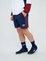 Bermuda deportiva Umbro del Club Nacional de Football, color azul marino, con cordón ajustable en la cintura, bolsillos laterales, el escudo del club en una pierna y el logo de la marca en la otra.