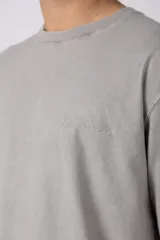 Remera de algodón gris con efecto acid wash, corte regular, mangas cortas y cuello redondo. Cuenta con un pequeño bordado tono sobre tono en el pecho y una etiqueta lateral distintiva de la marca en el ruedo.