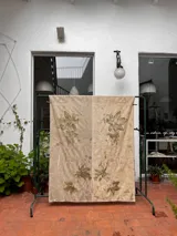 Mantel rectangular de lino y algodón en dos tonos, con estampado artesanal de hojas y flores.