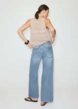 Jeans de denim celestes de tiro medio, diseño de corte recto y amplio con detalles de tachuelas en los bolsillos delanteros.