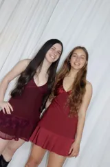 Vestido corto de tela metalizada en tono fucsia con reflejos dorados, con escote en V, diseño de top con triángulos, aberturas laterales en la cintura y doble volado irregular en el ruedo.