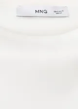 Camiseta sin mangas de color blanco, de diseño recto, con cuello redondo y hombreras, con corte peplum en la parte inferior.