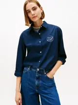 Camisa de Tommy Hilfiger azul marino, de manga larga con diseño ajustable tipo roll-tab, cuello camisero, cierre frontal con botones y logo gráfico bordado en el pecho.