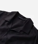 Camisa de lino blanca de corte boxy, manga corta, cuello bowling y cierre frontal de botones.