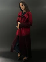 Tapado largo de lana merino color gris oscuro con teñido degradado en gris claro en ruedo, mangas y capucha. Tiene corte recto, bolsillos laterales y cierre cruzado con broches a presión ocultos en los hombros.