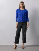 Cardigan blanco de tejido fino con abertura central y botones.