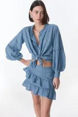 Camisa celeste de lino con botones, mangas largas abullonadas y detalles de crochet en el frente y los puños.