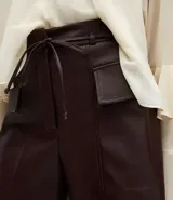 Short de tiro alto confeccionado en poliuretano con acabado brillante, presenta bolsillos delanteros con solapas estructuradas y cintura con elástico posterior. Incluye un cinto fino del mismo material para ajustar en la cintura.