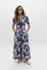 Pantalón de lino azul con estampado floral en tonos rosados y blancos, de tiro medio-alto, con tablas delanteras, bolsillos laterales y corte amplio.