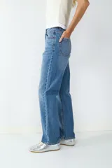 Jeans de tiro alto con corte recto, diseño clásico de cinco bolsillos, cierre frontal con cremallera y botón metálico.