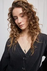 Campera de denim con diseño a rayas verticales y calce recto. Presenta escote en V, cierre frontal con botones metálicos y mangas largas.