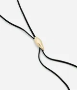 Collar largo estilo gravata con cordón negro de textura gamuzada y dije metálico en forma de gota con acabado dorado.