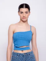 Top celeste de punto, con un solo hombro y corte en la cintura.