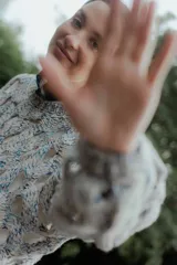 Buzo de tejido de punto calado con diseño de red, cuello redondo y mangas largas abullonadas. Presenta una textura jaspeada en tonos gris y blanco.