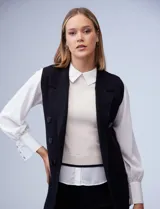 Chaleco largo tejido color blanco de la marca Sioni, con cuello solapa, doble botonadura dorada en el frente y bolsillos aplicados.