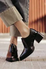 Zapato de cuero color beige, con taco de madera y suela dentada. Presenta un diseño slip-on con detalles de textura en relieve en los laterales y el empeine.