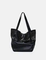 Bolso tote negro de cuero sintético con diseño holgado y dos asas de hombro. Presenta tachas metálicas redondas plateadas cubriendo la parte superior del cuerpo del bolso.