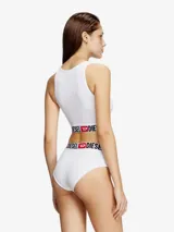 Top deportivo de algodón elástico color blanco, con cuello redondo y banda elástica ancha en la base con el logo de la marca estampado en contraste.