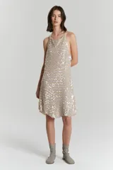 Vestido corto color beige con lentejuelas plateadas, de breteles finos y corte suelto.
