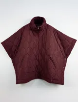 Poncho acolchado color vino tinto, con cuello alto y cierre frontal parcial. Presenta un patrón de costuras capitoné en forma de hoja o diamante y bolsillos delanteros.
