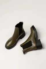 Bota tipo Chelsea de cuero color verde oliva, con paneles laterales elásticos negros y suela track de goma negra con taco cuadrado.