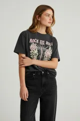 Remera de algodón de manga corta y cuello redondo, con diseño holgado y estampado gráfico frontal con motivos florales y tipografía vintage.