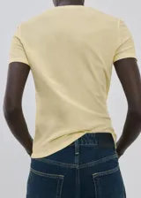Remera de algodón color amarillo claro, con mangas cortas, cuello redondo y costuras visibles a contratono en la parte frontal y laterales.