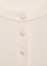Cardigan de punto fino color crema, con cuello redondo, manga larga y cierre frontal de botones al tono.