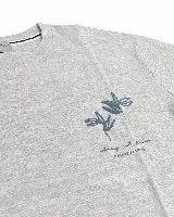 Remera negra de corte oversize y silueta relajada, con arte estampado en relieve en la espalda en color verde y textos decorativos.