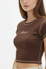 Remera cropped de algodón blanco, con cuello redondo y mangas cortas. Presenta costuras a contratono negras, dobladillos visibles y estampado de corazones en el pecho.