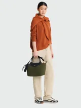 Cartera de mano modelo Le Pliage Energy en tamaño S, color verde oliva. Presenta solapa y asas de cuero negro, cierre principal con broche a presión y correa ajustable extraíble con detalles en blanco y negro.