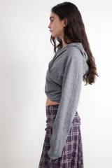 Jersey estilo sudadera gris con capucha, escote en pico y diseño cruzado en la parte frontal.
