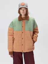 Campera acolchada de diseño colorblock, con el pecho y hombros en tono bordó y el cuerpo y mangas en color beige. Presenta cuello camisero y puños de pana negra, cierre frontal oculto con botones a presión y costuras pespuntadas en patrón cuadriculado.